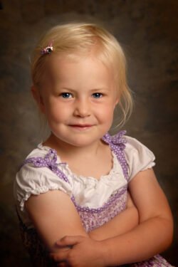 studio portrait with soft lighting of a smiling little girl with blonde hair
