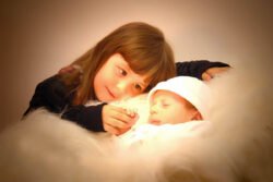 Young girl with baby brother holding hands with yellow toned