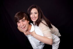portrait of young smiling couple with the girl on the guy's back and hugging him