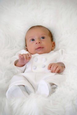 artistic portrait of newborn baby laying on white fur