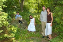 outdoor portrait of a family of 4 standing in a park or backyard